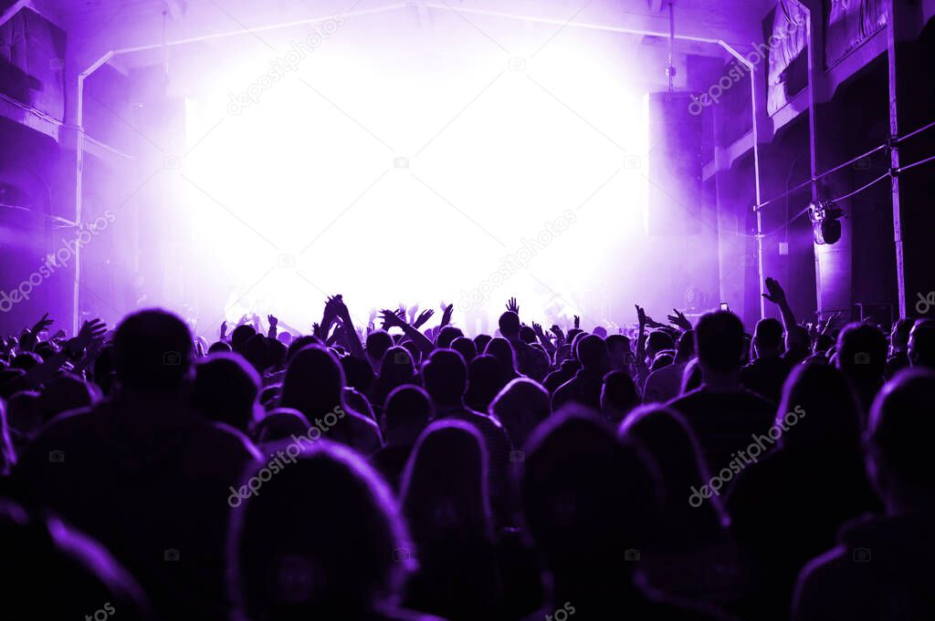 huge crowd in front of the stage at a music festival in purple light. banner or poster for the upcoming show. concert of a popular artist