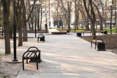 Bahar günü bankları olan boş temiz şehir parkı. İnsanlar karantinaya uyarlar. kamusal alanlara girme yasağı