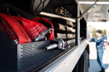 Kırmızı, itfaiye arabasındaki yangın hortumlarını sardı. Üniformalı bulanık adam. İtfaiye aracı hazır.