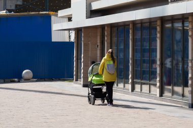 Genç bir kız bebek arabasında bir çocukla şehirde yürüyor. Bir bahar gününde bebeğiyle genç bir anne