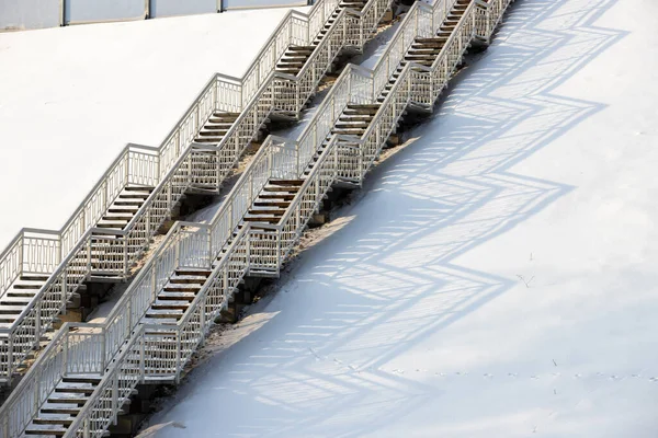 snow-covered steps on high stairs in the winter space. beautiful shadows from the handrails in the snow