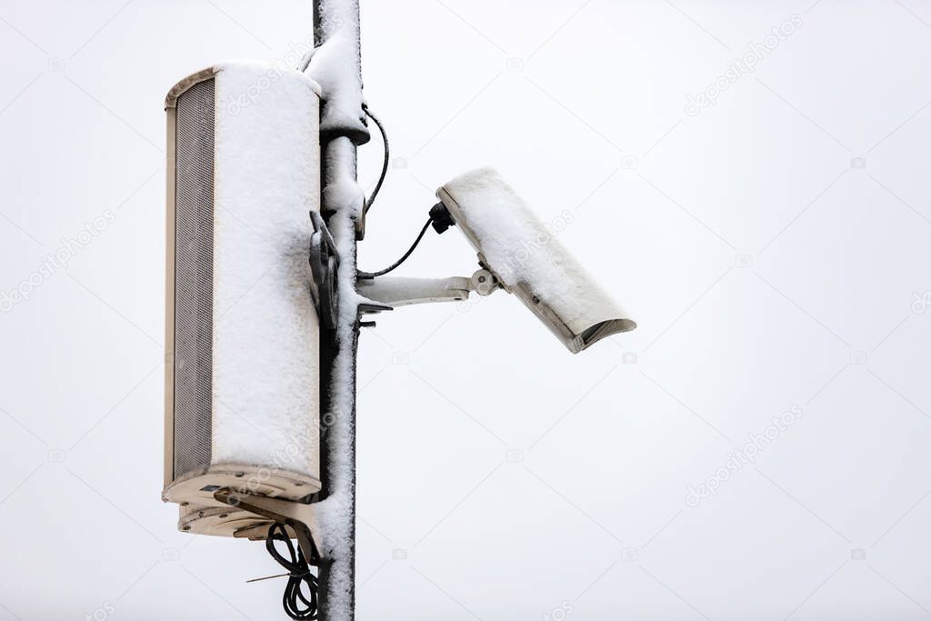 white street surveillance camera is covered in snow on the street. incident monitoring. Anti-theft system concept