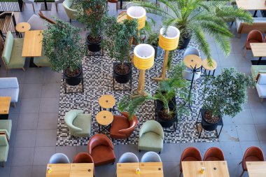 Saksı ağaçları ve yumuşak sandalyeleri olan güzel bir kafe manzarası. Havaalanının içindeki restoran. Alışveriş merkezindeki kafe.