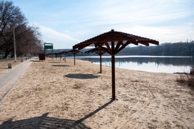 Nehir kenarında güneşlik olan boş kumlu bir sahil. Sadece sokak köpekleri şehir sahilinde yürür. Salgın içinde boş bir şehir