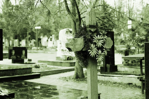墓地に人工の花を持つ木製の十字架の悲観的な写真 故人の親戚の墓 墓地の不気味な景色 — ストック写真