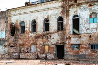 Kırık camları ve paslı boruları olan eski harap tuğla bina.