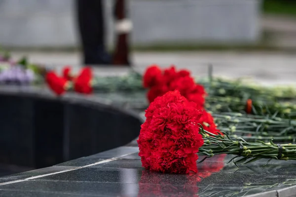 Garofani rossi su un monumento in marmo nero in memoria dei morti — Foto Stock