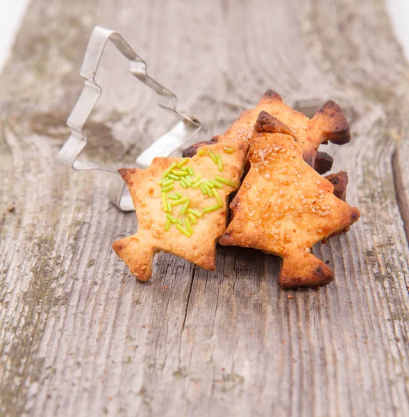 クリスマス ツリー型のクッキーと木製の背景にクッキー カッター — ストック写真