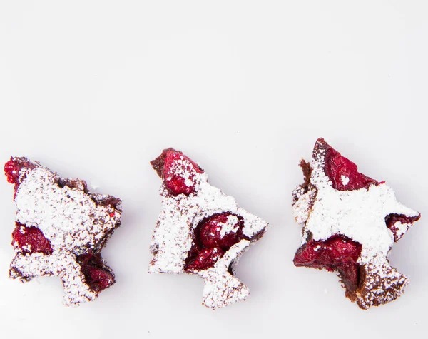 クリスマス ツリー形の白い背景の上に粉砂糖で覆われているラズベリーのブラウニー — ストック写真