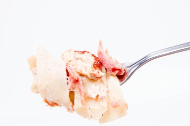 Pappardelle'i krem, kurutulmuş domates ve bir çatal üzerinde füme balık