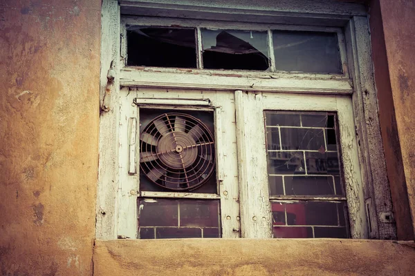 Old building with a broken window with an air-con fan