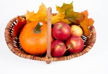 Beyaz bir arka plan üzerinde sepet dolu bir kabak ve elma ile bazı akçaağaç yaprakları