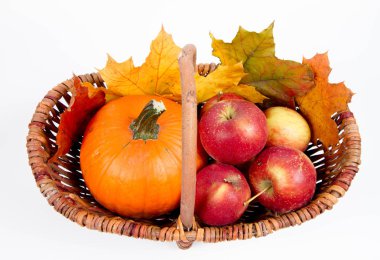 Beyaz bir arka plan üzerinde sepet dolu bir kabak ve elma ile bazı akçaağaç yaprakları