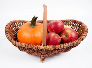Sepet beyaz zemin üzerinde bir kabak ve elma dolu