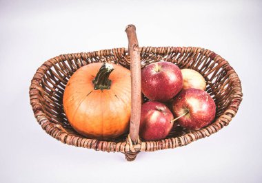 Sepet beyaz zemin üzerinde bir kabak ve elma dolu