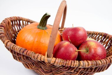 Sepet beyaz zemin üzerinde bir kabak ve elma dolu