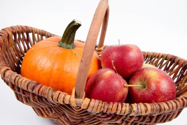 Sepet beyaz zemin üzerinde bir kabak ve elma dolu