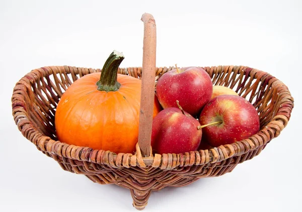 Sepet beyaz zemin üzerinde bir kabak ve elma dolu