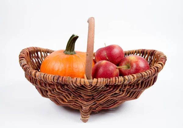 Sepet beyaz zemin üzerinde bir kabak ve elma dolu