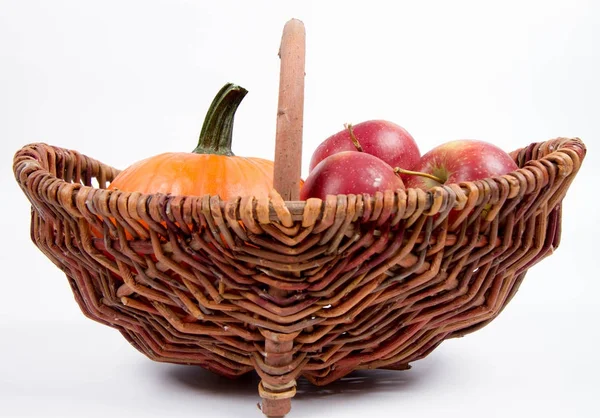 Sepet beyaz zemin üzerinde bir kabak ve elma dolu