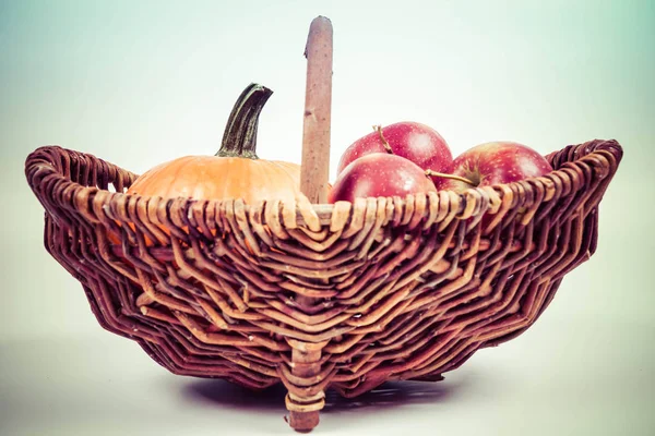 Sepet beyaz zemin üzerinde bir kabak ve elma dolu