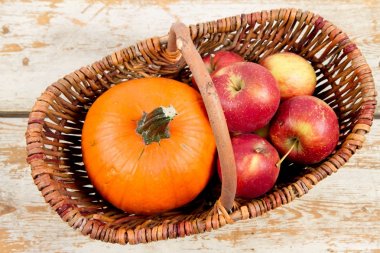 Sepeti ahşap arka plan üzerinde bir kabak ve elma dolu