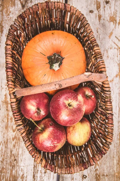 Sepeti ahşap arka plan üzerinde bir kabak ve elma dolu