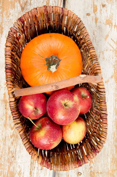 Sepeti ahşap arka plan üzerinde bir kabak ve elma dolu