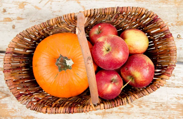 Sepeti ahşap arka plan üzerinde bir kabak ve elma dolu