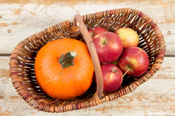 Sepeti ahşap arka plan üzerinde bir kabak ve elma dolu