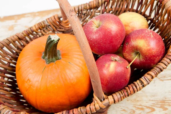 Sepeti ahşap arka plan üzerinde bir kabak ve elma dolu