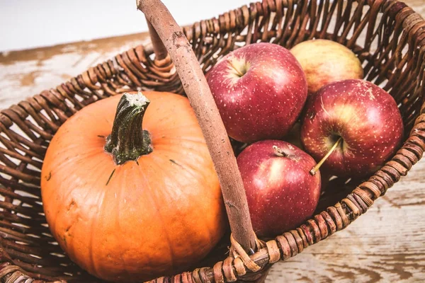 Sepeti ahşap arka plan üzerinde bir kabak ve elma dolu