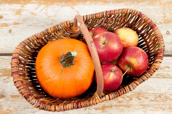 Sepeti ahşap arka plan üzerinde bir kabak ve elma dolu