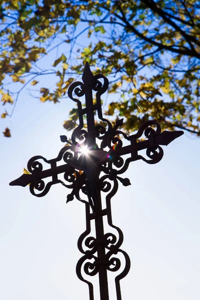 Old cross at a cemetery against a blue sky