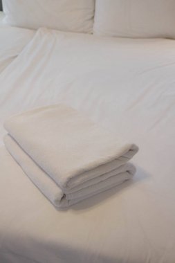 Bir otel odasında bir yatak üzerinde havlu yığını 