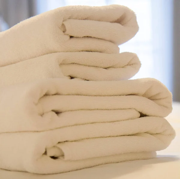 一叠毛巾在一张床在旅馆房间与窗口在背景 — 图库照片