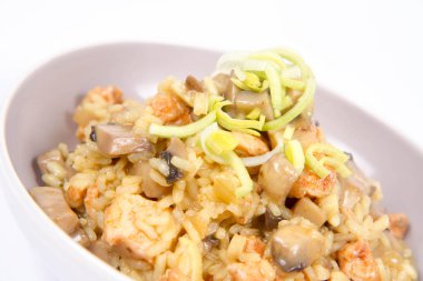 Risotto mantar ve beyaz zemin üzerine pırasa ile dekore edilmiş tavuk 