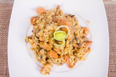 Risotto mantar ve beyaz zemin üzerine pırasa ile dekore edilmiş tavuk