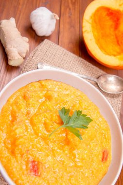 Balkabağı çorbası ve kabak, kabak çekirdeği, zencefil ve sarımsak ahşap arka plan üzerinde