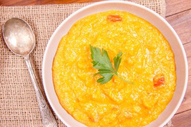 Kabak ve havuç çorbası bir ahşap zemin üzerine krema, maydanoz ve balkabağı tohumları ile dekore edilmiş