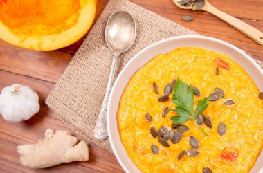 Balkabağı çorbası ve kabak, kabak çekirdeği, zencefil ve sarımsak ahşap arka plan üzerinde