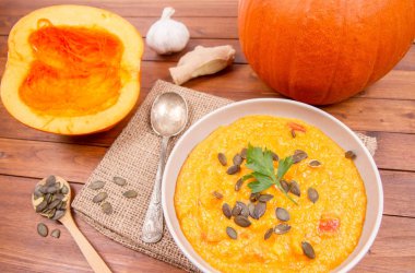 Balkabağı çorbası ve kabak, kabak çekirdeği, zencefil ve sarımsak ahşap arka plan üzerinde