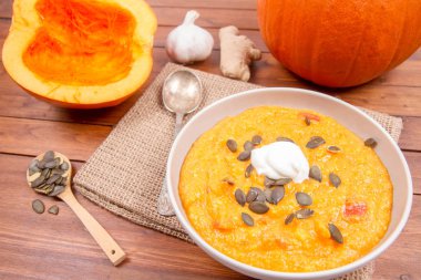 Balkabağı çorbası ve kabak, kabak çekirdeği, zencefil ve sarımsak ahşap arka plan üzerinde