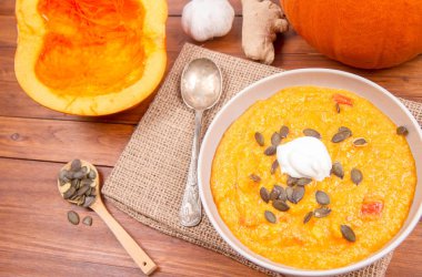 Balkabağı çorbası ve kabak, kabak çekirdeği, zencefil ve sarımsak ahşap arka plan üzerinde