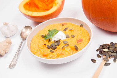 Balkabağı çorbası ve kabak, kabak çekirdeği, zencefil ve sarımsak beyaz bir arka plan üzerinde