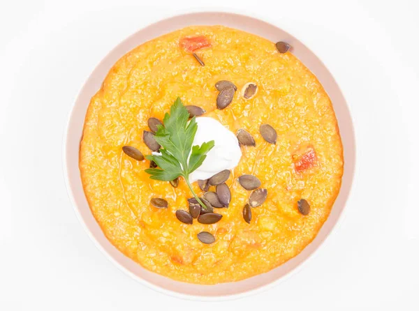 Kabak ve havuç çorbası Krem, maydanoz ve balkabağı tohumları üzerinde beyaz bir arka plan ile dekore edilmiş