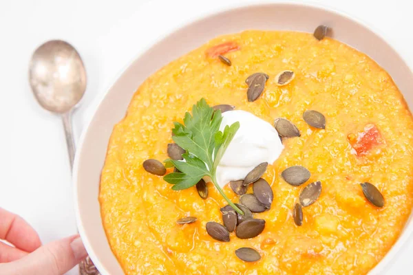 Kabak ve havuç çorbası Krem, maydanoz ve balkabağı tohumları üzerinde beyaz bir arka plan ile dekore edilmiş