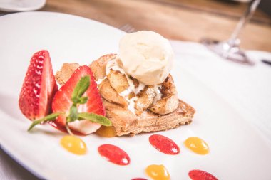 Elmalı turta dondurma çilek ile dekore edilmiş meyve sosu ve bitki bir restoranda servis