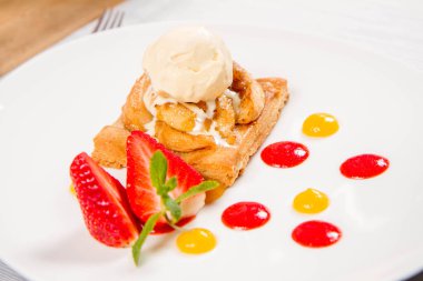 Bir çilek, meyve sosu ve bitki beyaz zemin üzerine elmalı pasta dondurma ile süslenmiş