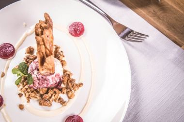 Lehçe-Litvanyaca geleneksel bir restoranda taze nane ile dekore edilmiş dondurma, kavrulmuş fındık ve ahududulu jöle ile pasta ('ağaç kek') - sekacz (Polonya) veya sakotis (Litvanyaca) tükürmek